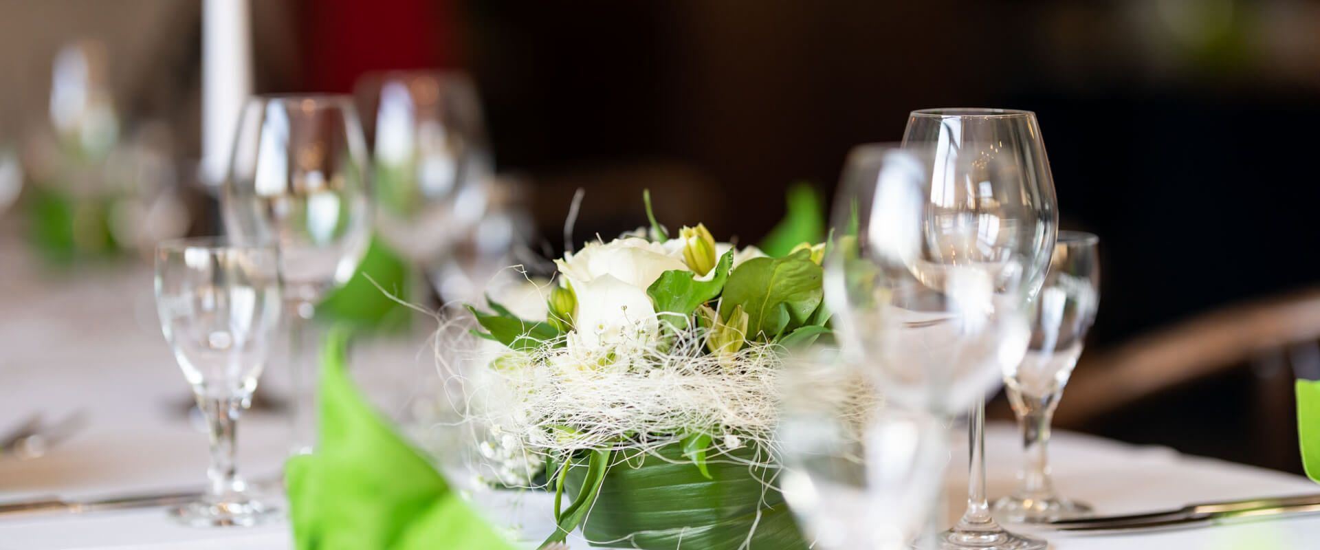 Gedeckter Tisch im Restaurant Lübsche Thorweide mit Gläsern, grünen Servietten und Blumenarrangement